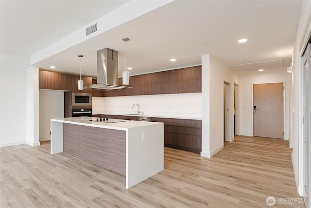 kitchen with a sink, modern cabinets, island exhaust hood, and visible vents