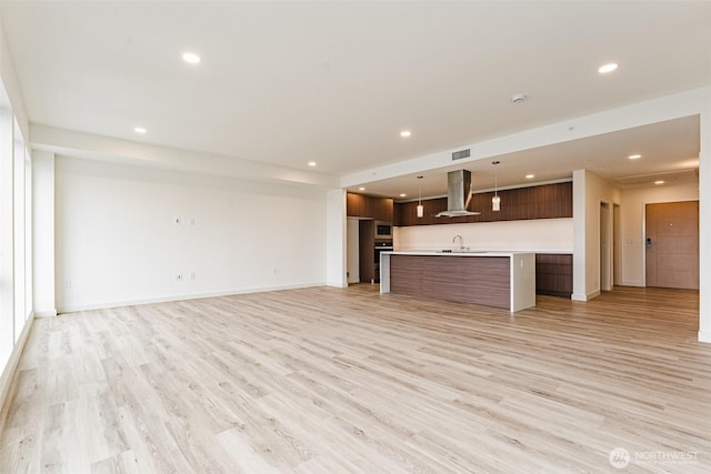 unfurnished living room with light wood finished floors, a sink, and recessed lighting