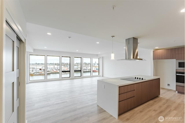 kitchen with brown cabinets, black electric stovetop, island range hood, modern cabinets, and light wood-type flooring