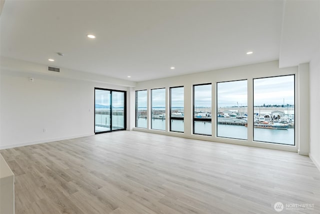 empty room featuring baseboards, light wood finished floors, visible vents, and recessed lighting