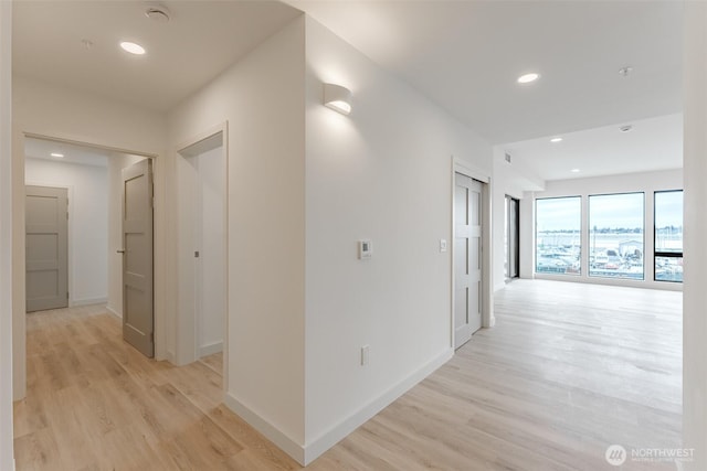 corridor featuring light wood-type flooring, baseboards, and recessed lighting