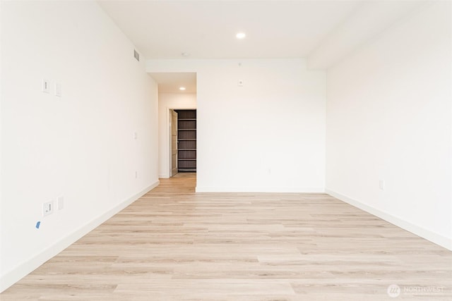 empty room with light wood finished floors, recessed lighting, visible vents, and baseboards