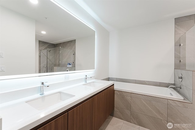 full bathroom with double vanity, a stall shower, tiled tub, and a sink