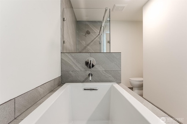 bathroom featuring a tub, toilet, and a walk in shower