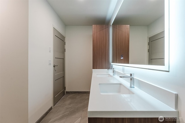 full bathroom featuring a sink, baseboards, and double vanity