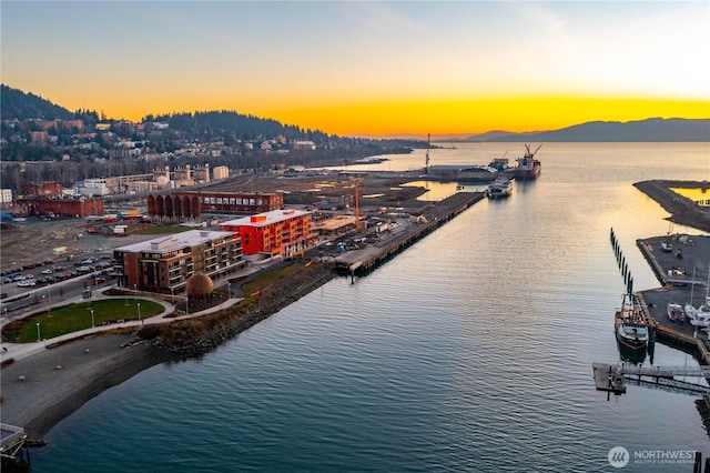 aerial view at dusk featuring a water and mountain view