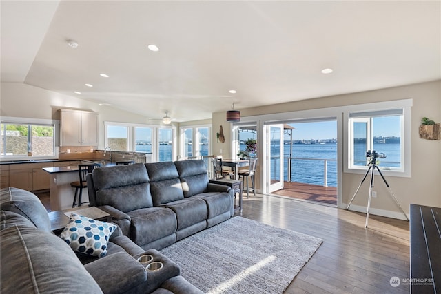 living room with vaulted ceiling, ceiling fan, a water view, and hardwood / wood-style floors