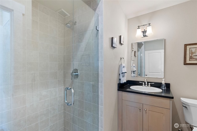 bathroom featuring an enclosed shower, vanity, and toilet