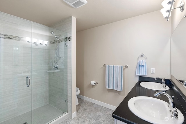 bathroom featuring a shower with shower door, dual vanity, toilet, and tile floors