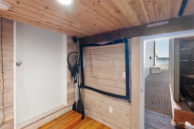 interior space featuring wood walls, hardwood / wood-style flooring, a water view, and wooden ceiling