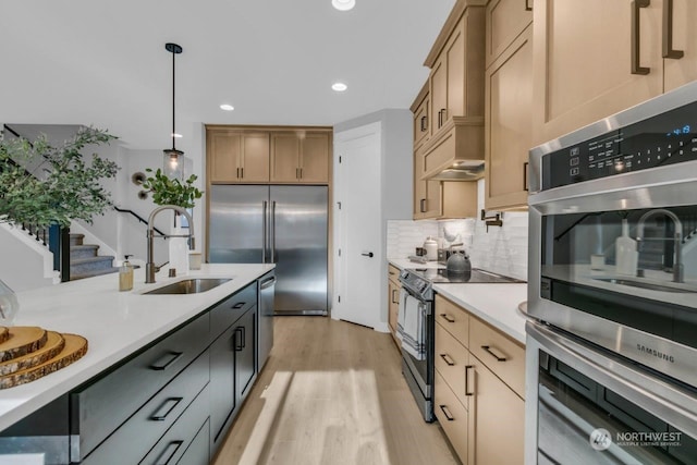 kitchen featuring sink, light wood-type flooring, appliances with stainless steel finishes, pendant lighting, and backsplash