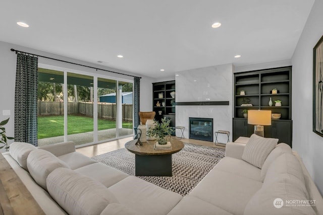 living room with built in shelves, a high end fireplace, and hardwood / wood-style floors