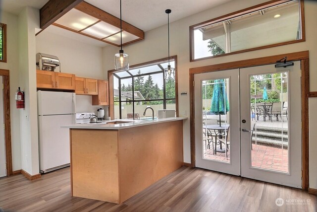 kitchen featuring white refrigerator, kitchen peninsula, hanging light fixtures, light wood-type flooring, and french doors