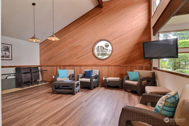 living room featuring wooden walls, high vaulted ceiling, and wood-type flooring