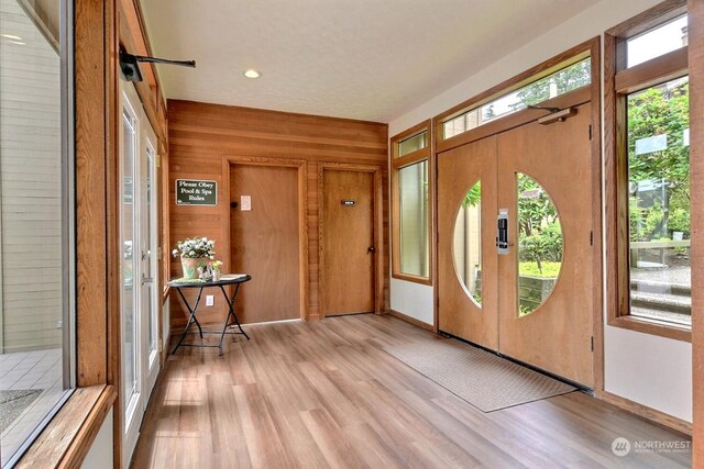 foyer entrance featuring wooden walls and light wood-type flooring