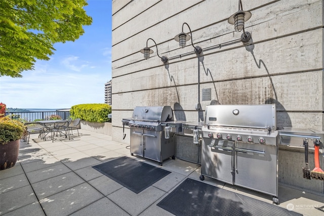 view of patio featuring grilling area, exterior kitchen, and a water view