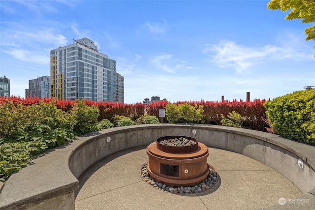 surrounding community featuring a view of city, a patio, and an outdoor fire pit