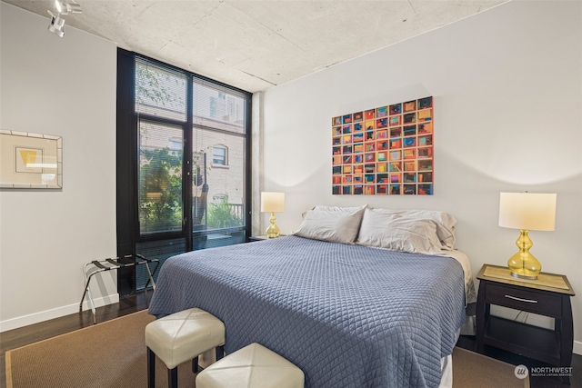 bedroom with a wall of windows, wood finished floors, and baseboards