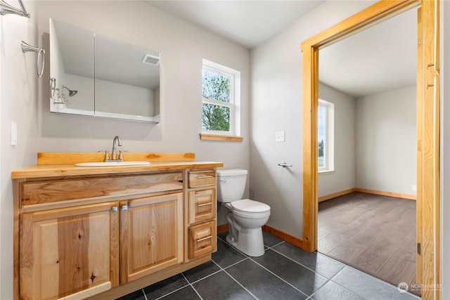 bathroom featuring tile floors, vanity, and toilet