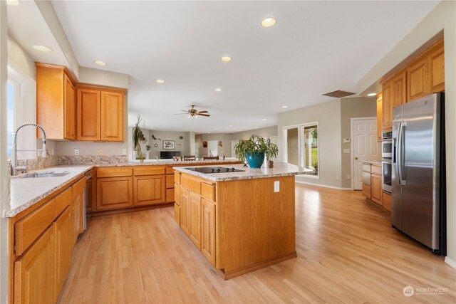 kitchen with sink, a kitchen island, light hardwood / wood-style floors, and appliances with stainless steel finishes