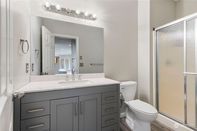 bathroom featuring vanity, wood-type flooring, toilet, and walk in shower