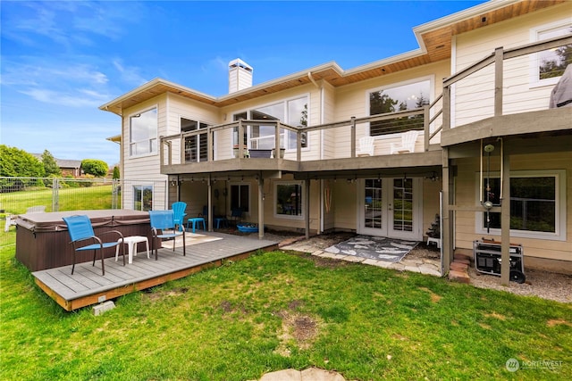 rear view of house with french doors, a hot tub, a lawn, a deck, and a patio