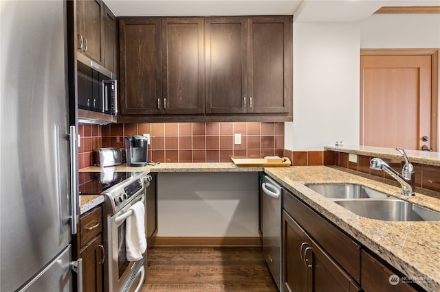 kitchen featuring light stone countertops, dark hardwood / wood-style flooring, stainless steel appliances, backsplash, and sink