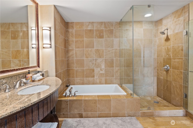 bathroom featuring tile walls, tile flooring, shower with separate bathtub, and vanity