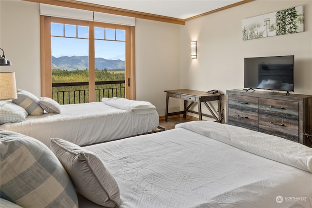 bedroom featuring multiple windows, wood-type flooring, a mountain view, and access to outside