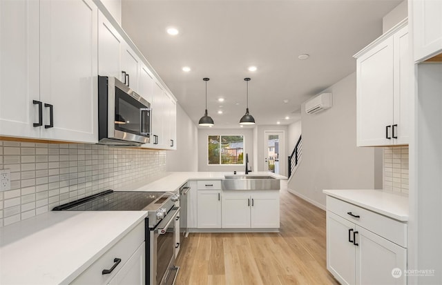 kitchen featuring sink, hanging light fixtures, stainless steel appliances, a wall mounted AC, and white cabinets