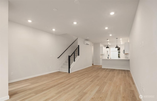 unfurnished living room featuring light wood-type flooring and a wall unit AC