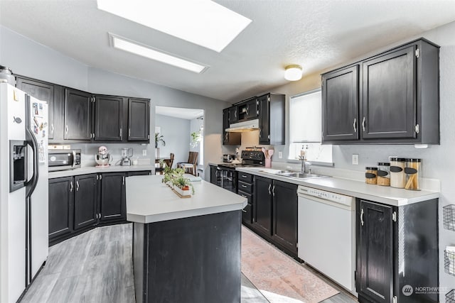 kitchen with white appliances, light wood-type flooring, a kitchen island, sink, and lofted ceiling