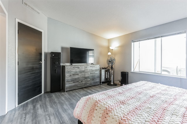 bedroom featuring a textured ceiling, wood-type flooring, and vaulted ceiling