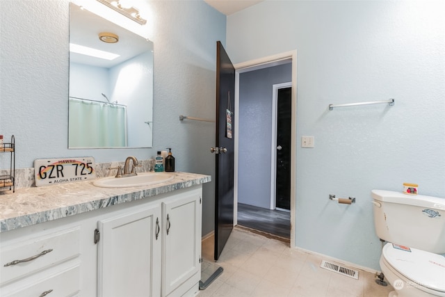 bathroom featuring tile floors, vanity, and toilet