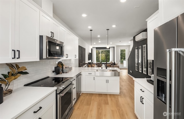 kitchen featuring decorative light fixtures, light hardwood / wood-style floors, backsplash, premium appliances, and white cabinets