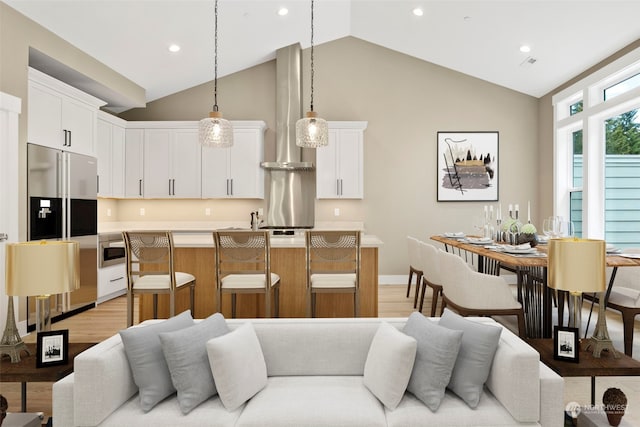 living room featuring high vaulted ceiling and light hardwood / wood-style flooring