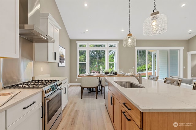 kitchen with light wood-type flooring, stainless steel appliances, a kitchen island with sink, wall chimney exhaust hood, and sink