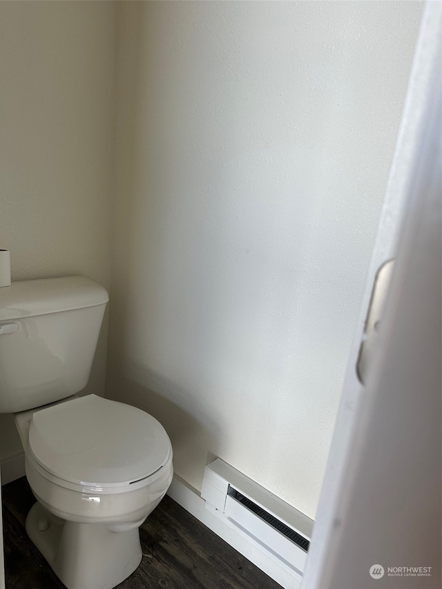 bathroom featuring a baseboard heating unit, toilet, and hardwood / wood-style floors