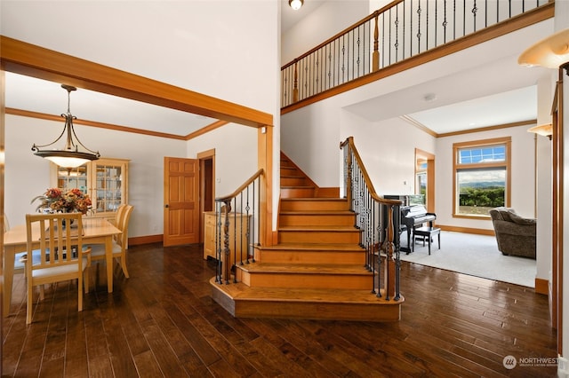 stairs featuring dark hardwood / wood-style floors, ornamental molding, and a high ceiling