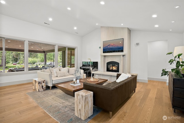 living room with lofted ceiling, a large fireplace, and light wood-type flooring