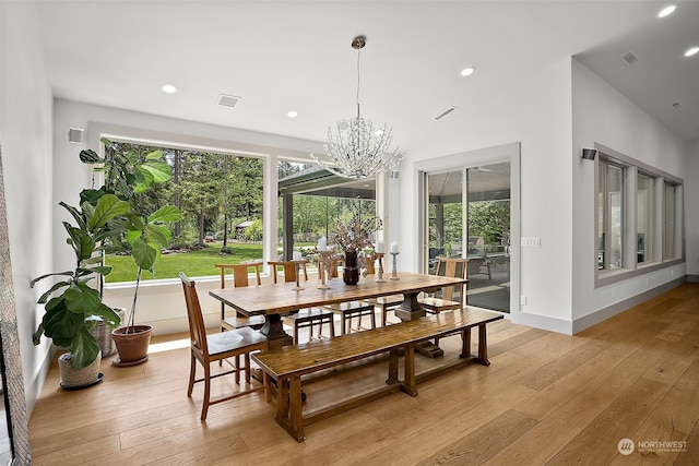 dining room with light hardwood / wood-style floors, a wealth of natural light, and an inviting chandelier