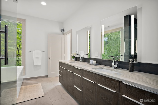 bathroom with a bath to relax in, tile floors, double sink, and vanity with extensive cabinet space