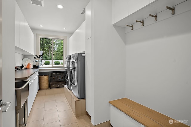 interior space featuring washer and dryer, sink, light tile flooring, and cabinets