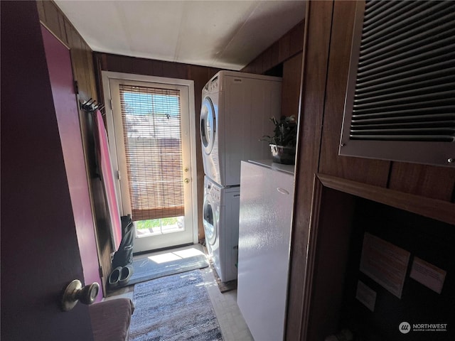 entryway with a wealth of natural light, wooden walls, and stacked washer / dryer