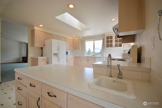 kitchen featuring light brown cabinets, white appliances, a skylight, and sink