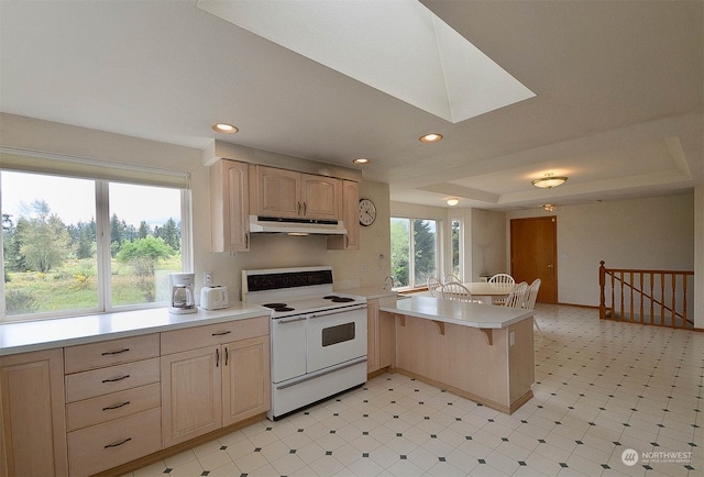 kitchen with kitchen peninsula, electric range, light brown cabinets, and a wealth of natural light