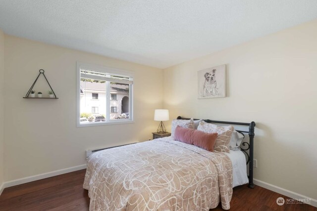 bedroom with a textured ceiling, dark hardwood / wood-style floors, and a baseboard radiator