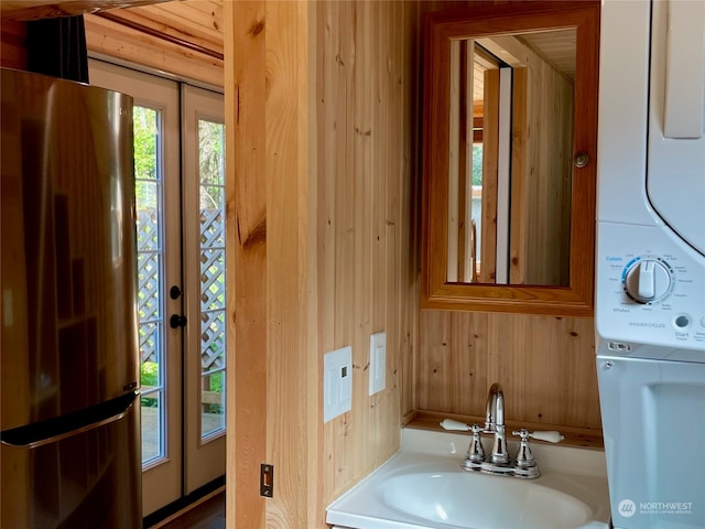 bathroom with sink, wood walls, and stacked washer / drying machine