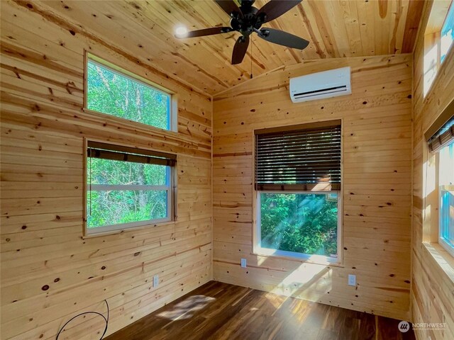 spare room with ceiling fan, wood ceiling, wood-type flooring, an AC wall unit, and wood walls