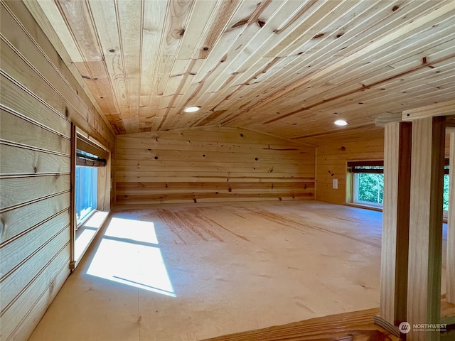 empty room with wooden ceiling, lofted ceiling, and wooden walls